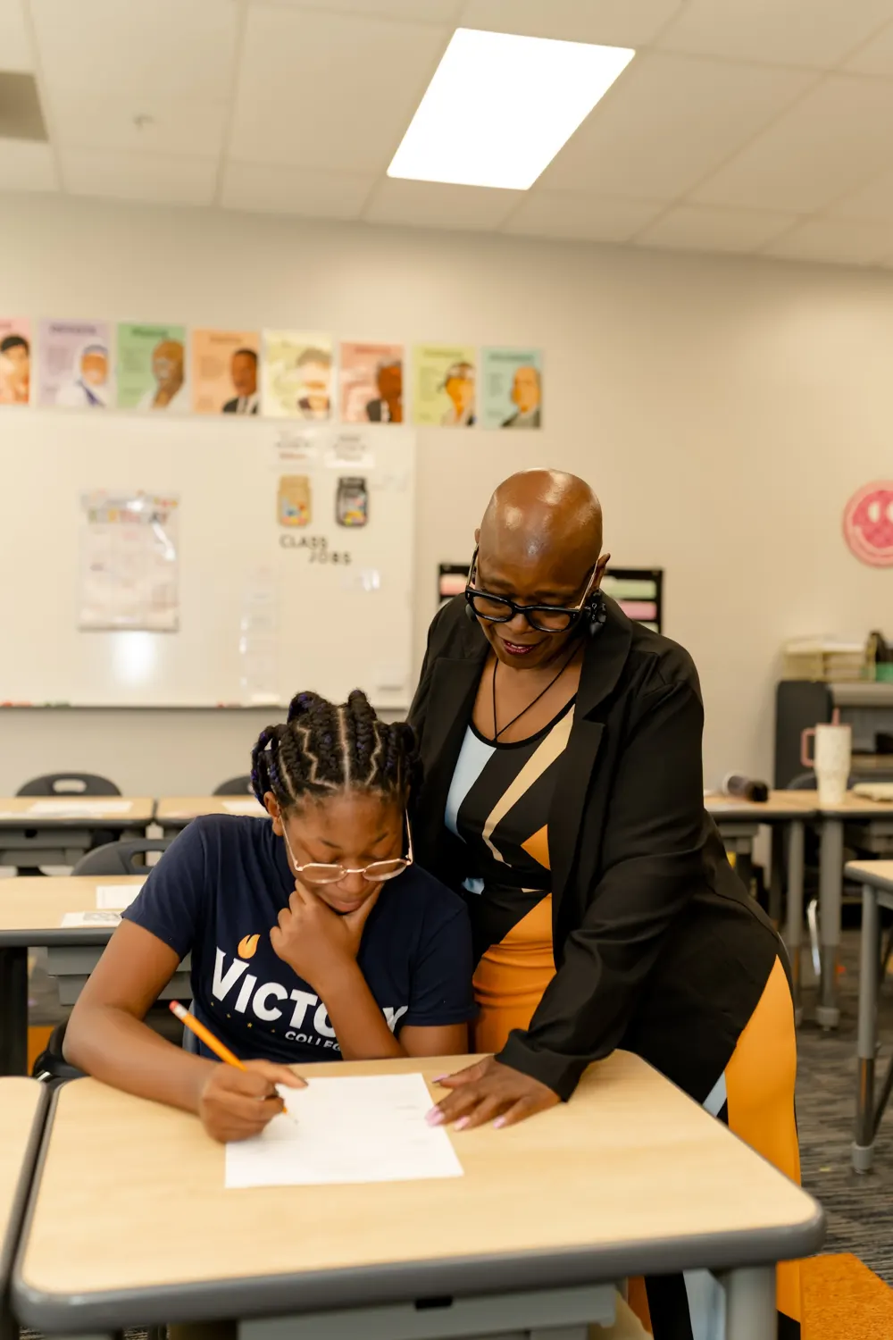 Angelia Moore helping a student with her writing at a desk